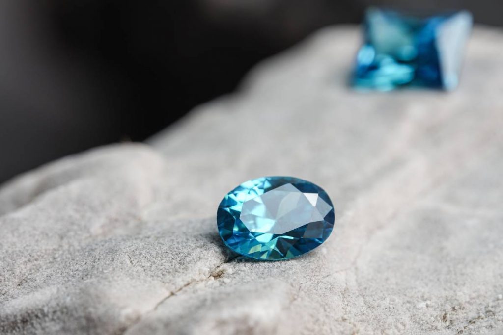 A glimmering natural blue sapphire gemstone on a rock surface