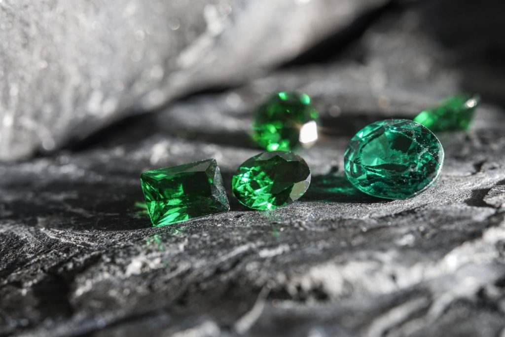 The glimmering natural green sapphire gemstones on a rugged rock surface