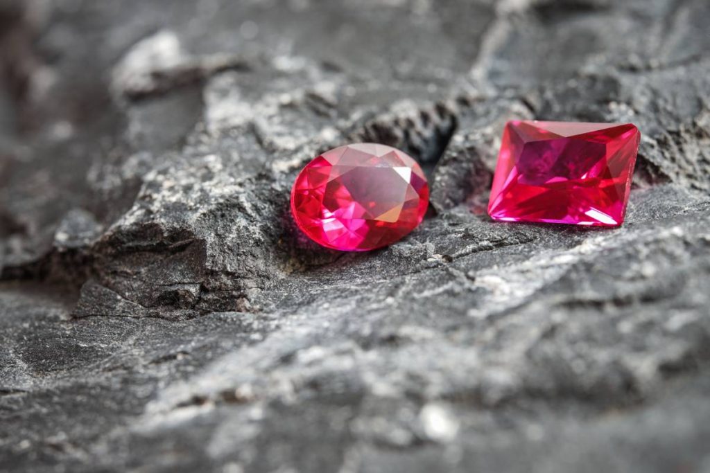 The glimmering natural pink sapphire gemstones on a rugged rock surface