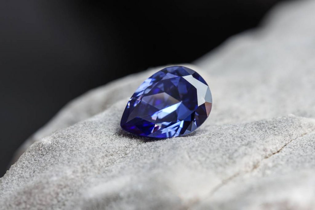 A glimmering natural purple sapphire gemstone on a rock surface