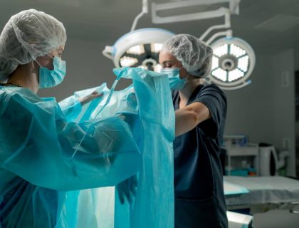 in a modern clinic in a bright spacious operating room, the doctor, the surgeon, with sterile hands, is ready to put on a surgical gown and gloves, the nurse helps to get dressed