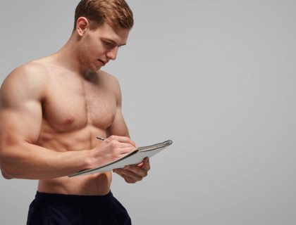 Bodybuilder writing in notepad